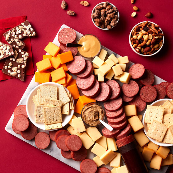 All Day Celebration Gift Box meat and cheese sliced and arranged on board with mustard, crackers, candy, and nuts
